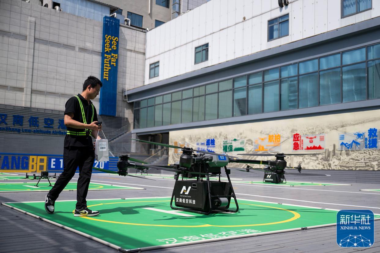 ↑ 6月16日，在汉商低空港停机坪，一名工作人员给无人机装配货物。